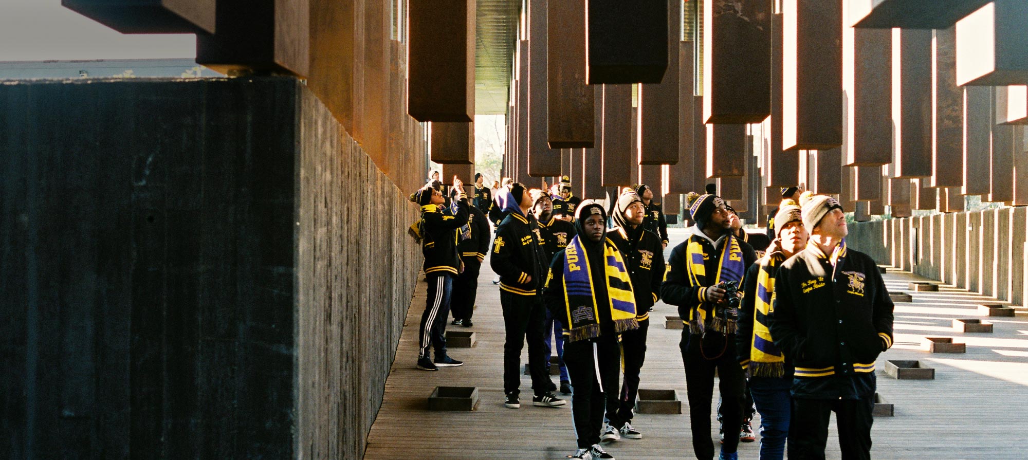 Members of a fraternity in matching jackets and scarves visit the National Memorial for Peace and Justice.