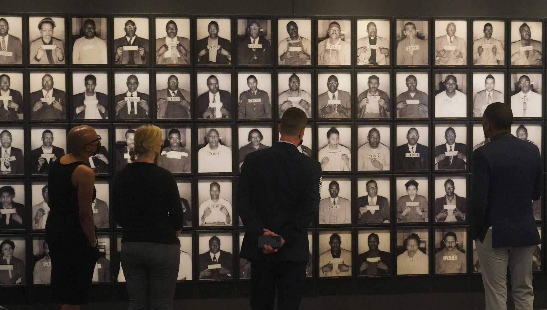 Visitors to the Legacy Museum gaze upon the booking photographs of the dozens of people who were arrested for taking part in the Montgomery Bus Boycott, including Rosa Parks and Dr. Martin Luther King Jr.