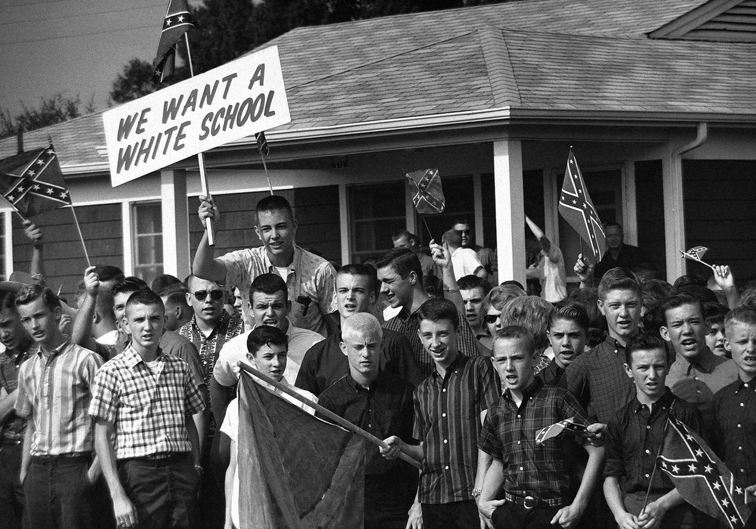 Young boys wave Confederate flags and a sign that reads 