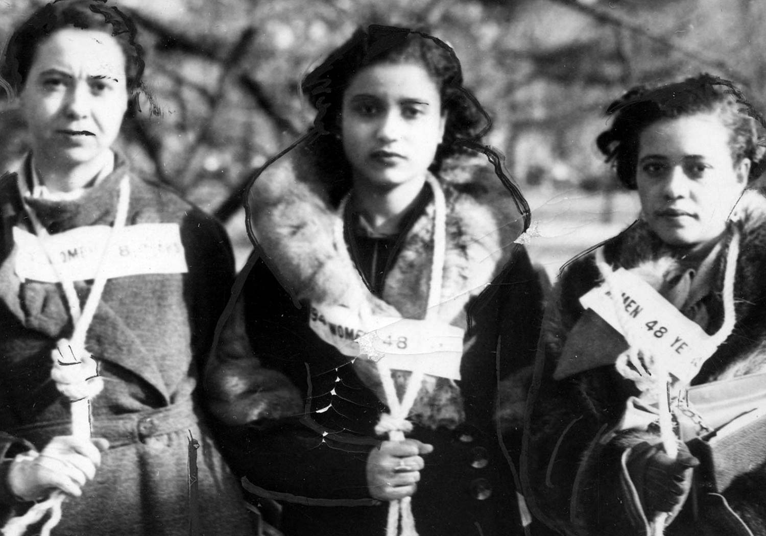 Three young women wear signs and nooses around their necks while protesting against lynchings.